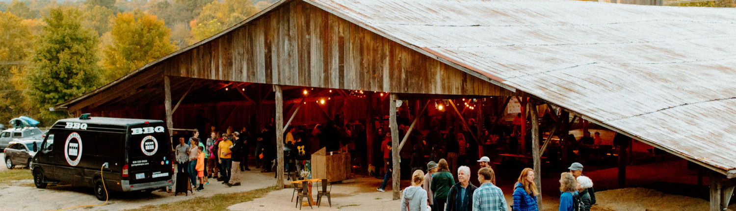 group gathered outside barn at Hickory Nut Gap Farm with food truck, fall colors in trees