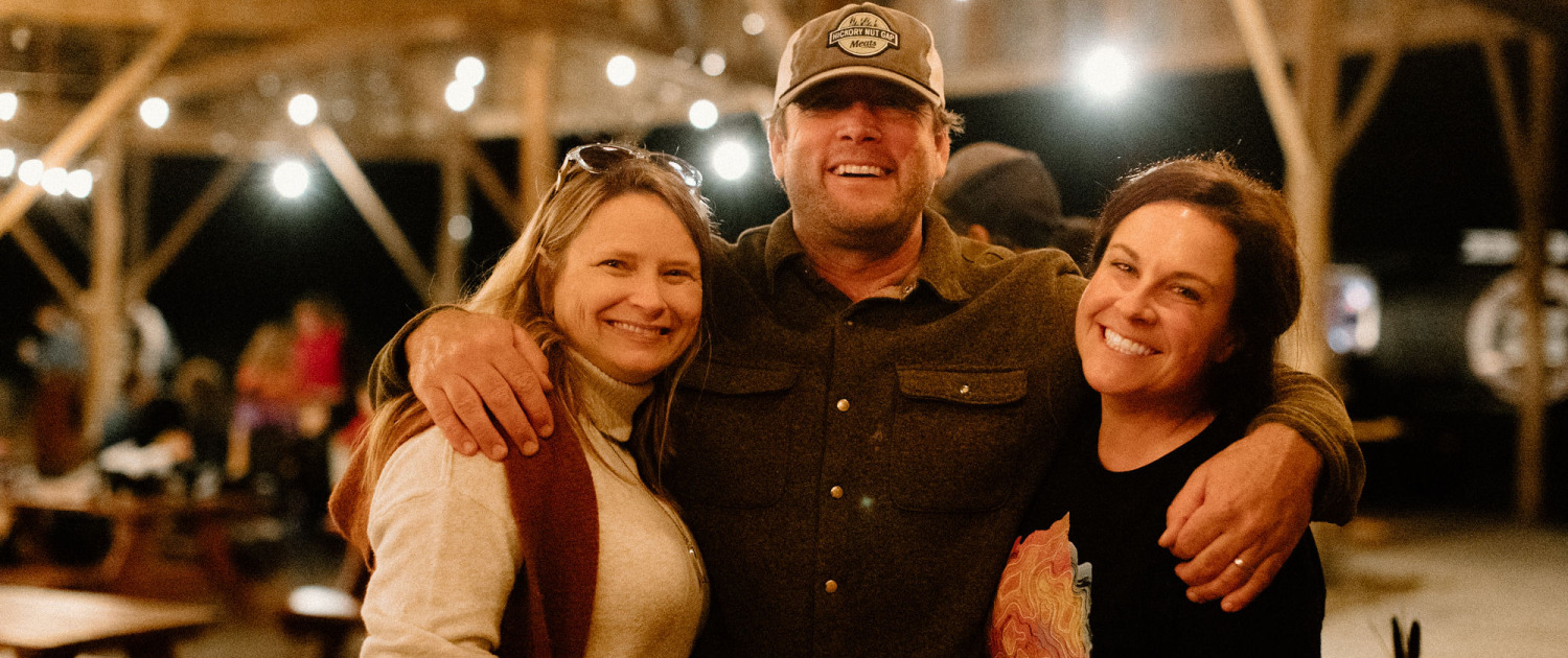 Cheryl, Jamie, and Rachel posing in a huddle in barn after dark