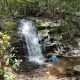 Child playing in shallow water at base of small waterfall