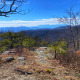 View from rocky opening over rolling blue and green mountains in the distance.